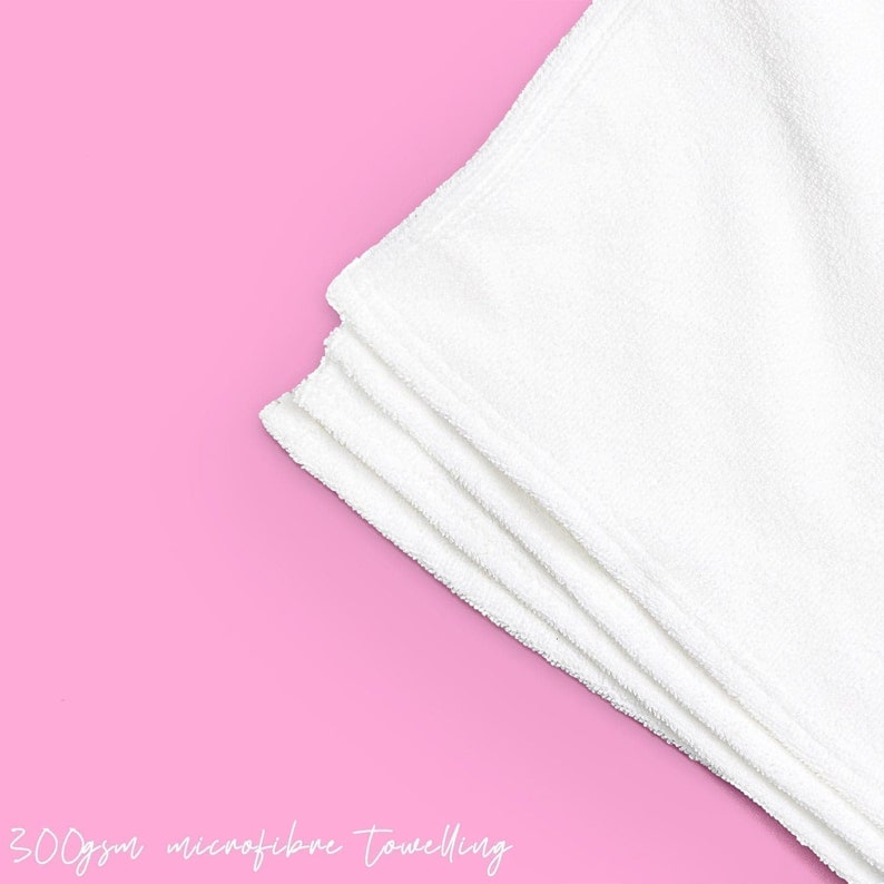 May include: A stack of four white microfiber towels on a pink background. 300gsm microfiber toweling.