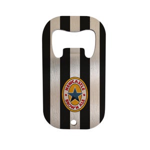May include: Bottle opener with a black and white striped design. The opener features the Newcastle Brown Ale logo in the center. The opener has a hole at the bottom for easy storage.