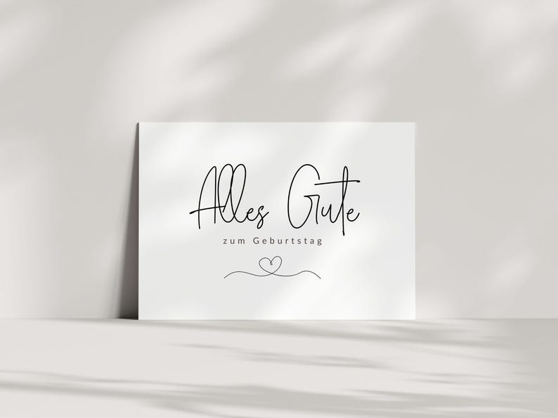 May include: A white card with black text that reads "Alles Gute zum Geburtstag" with a small heart drawn below the text.