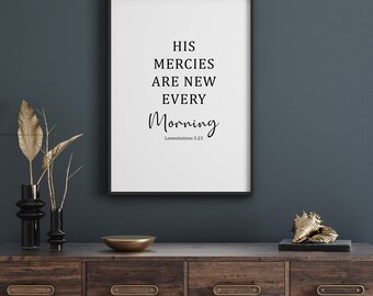 May include: A black framed print with the text "HIS MERCIES ARE NEW EVERY MORNING" and the scripture reference "Lamentations 3:23". The print is hanging on a dark blue wall above a wooden dresser with gold hardware.