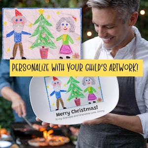 May include: A white oval plate featuring a child's drawing of a Christmas scene with a Santa Claus figure, a Christmas tree, and a woman. The plate has the text "Merry Christmas!" and "Personalize with your child's artwork!"