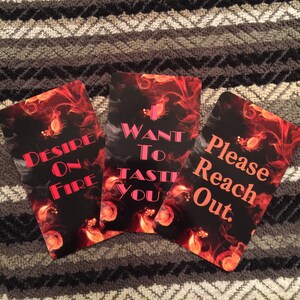 Puede incluir: Tres cartas con un fondo de fuego y texto rosa. La primera carta dice "Desire on Fire". La segunda carta dice "Want to Taste You". La tercera carta dice "Please Reach Out."