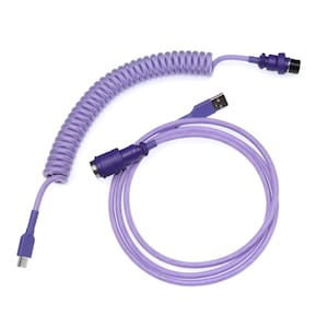 Op de afbeelding: Een paars gekleurde, opgerolde toetsenbordkabel met een USB-connector en een andere connector. De kabel is ontworpen voor mechanische toetsenborden en heeft een opgerold gedeelte voor flexibiliteit en een recht gedeelte voor aansluiting op een computer.