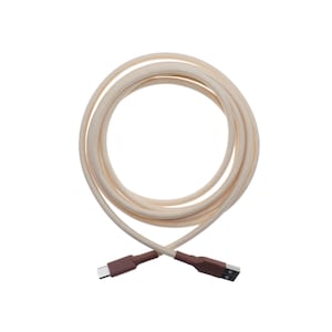May include: A coiled beige USB charging cable with brown connectors. The cable is made of a woven material and has a USB-A connector on one end and a USB-C connector on the other. The background is white.