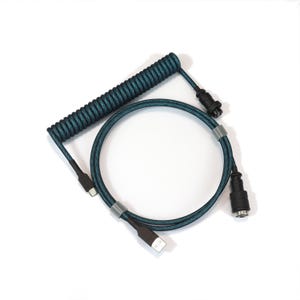 Op de afbeelding: Een teal en zwarte gekrulde toetsenbordkabel met een USB-C-connector en een USB-A-connector. De kabel heeft een gekruld gedeelte en een recht gedeelte, met een connector aan elk uiteinde. Ontworpen voor mechanische toetsenborden.