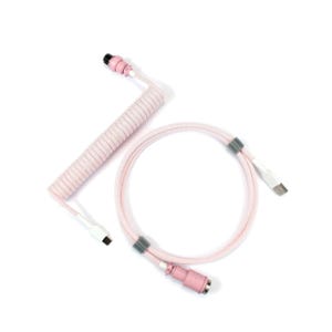 Op de afbeelding: Een roze USB-kabel met spiraal, recht gedeelte en connectoren. De kabel heeft een lichtroze stoffen bekleding en beschikt over een USB-A- en een USB-C-connector. Het opgerolde gedeelte bevindt zich bovenaan, met een recht gedeelte en een USB-C-connector onderaan.