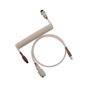 May include: A beige coiled cable with brown connectors and a USB connector. The cable has a spiral design and is designed for connecting devices. The connectors are a light beige colour and the cable is on a white background.