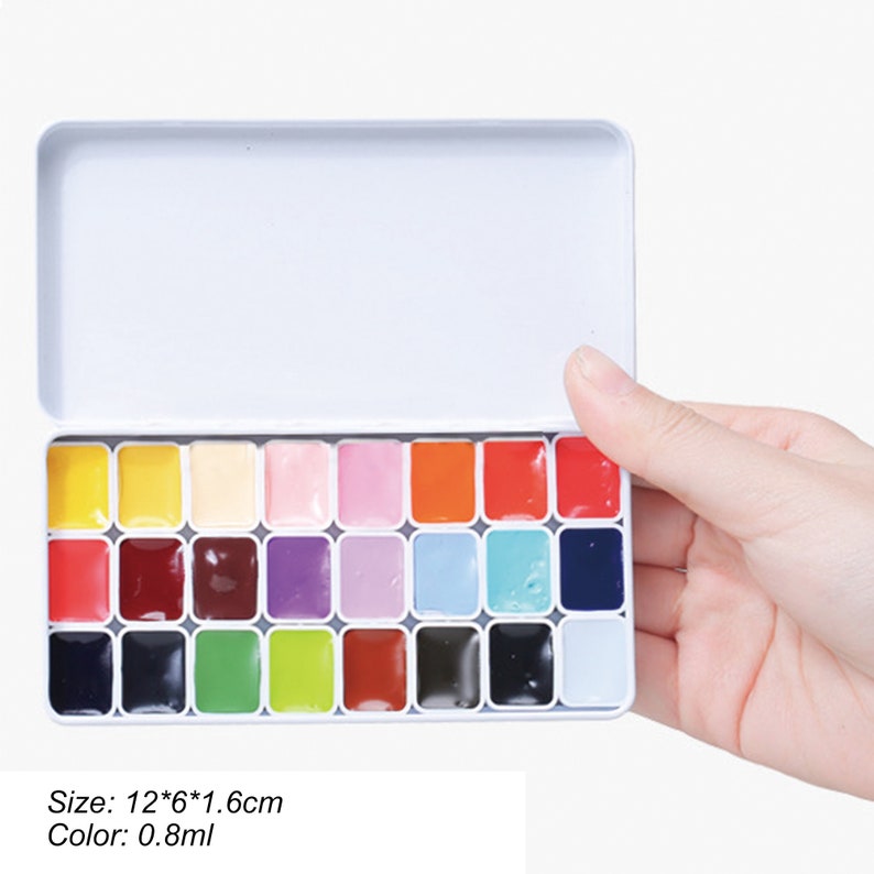 May include: A white metal tin with a lid containing 24 watercolor paint pans. The pans are arranged in four rows of six. The colors include yellow, orange, red, pink, purple, blue, green, brown, black, and white. The tin is 12 inches by 6 inches by 1.6 inches. Each paint pan contains 0.8 ml of paint. Size: 12*6*1.6cm Color: 0.8ml
