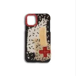 May include: Black phone case with a patchwork design featuring different colored fabrics and red cross stitching.