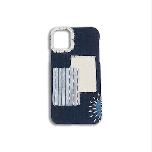 Puede incluir: Una funda de teléfono de mezclilla azul con un diseño de patchwork que presenta cuadrados de tela blanca y azul y un círculo azul con costuras blancas.