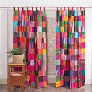 Op de afbeelding: Twee kleurrijke patchwork gordijnen met een verscheidenheid aan felle kleuren en patronen, waaronder rood, roze, paars, blauw, groen, geel en oranje. De gordijnen zijn gemaakt van een zachte, geweven stof en hebben een rustieke, bohemian stijl.