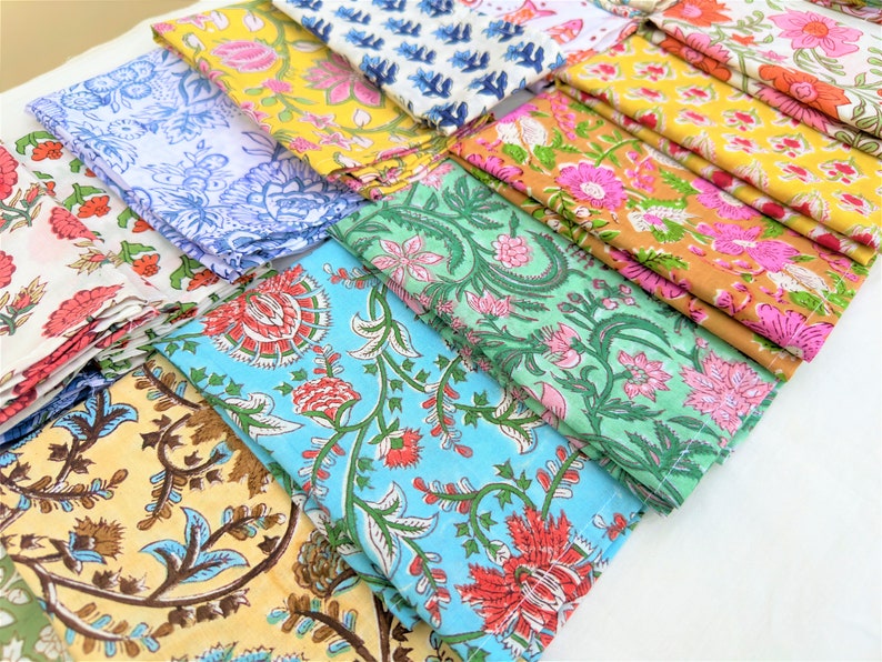 May include: A stack of colorful fabric napkins with floral patterns. The napkins are made of cotton and are perfect for adding a touch of elegance to any table setting.