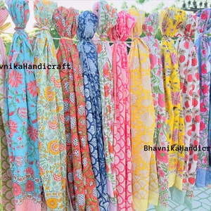 May include: A collection of colorful cotton scarves with floral and geometric patterns. The scarves are tied together with string and hang from a clothesline. The text "BhavnikaHandicraft" appears twice on the scarves.