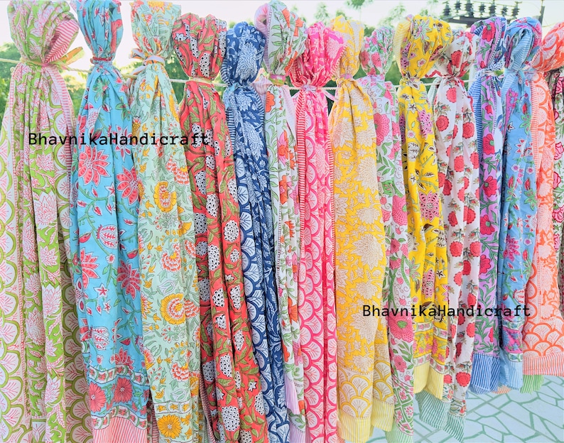 May include: A collection of colorful cotton scarves with floral and geometric patterns. The scarves are tied together with string and hang from a clothesline. The text "BhavnikaHandicraft" appears twice on the scarves.