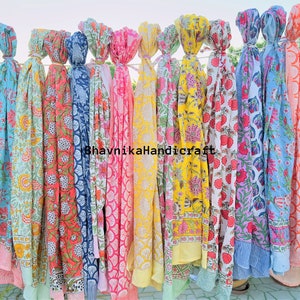 May include: A collection of 15 colorful cotton scarves with floral patterns. The scarves are hanging on a clothesline and are all different colors and designs. The scarves are all made of cotton and are soft and comfortable to wear.