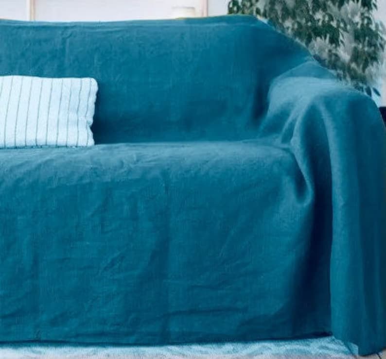 Peut inclure: Une couverture en lin bleu sarcelle drap&eacute; sur un canap&eacute;. La couverture est douce et textur&eacute;e, et elle serait parfaite pour ajouter une touche de couleur et de chaleur &agrave; n'importe quel salon.