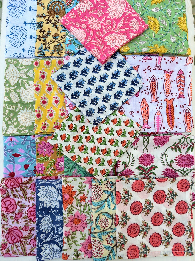 May include: A collection of 20 colorful fabric squares with various floral and geometric patterns. The squares are arranged in a grid pattern and are all folded in half.