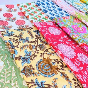 May include: A collection of colorful fabric squares with floral patterns. The fabrics are arranged in a staggered pattern, with the top fabric squares overlapping the bottom ones. The fabrics are all different colors and patterns, including pink, red, blue, green, and yellow.