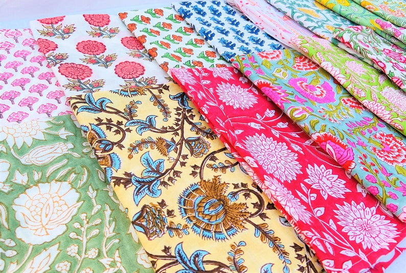 May include: A collection of colorful fabric squares with floral patterns. The fabrics are arranged in a staggered pattern, with the top fabric squares overlapping the bottom ones. The fabrics are all different colors and patterns, including pink, red, blue, green, and yellow.