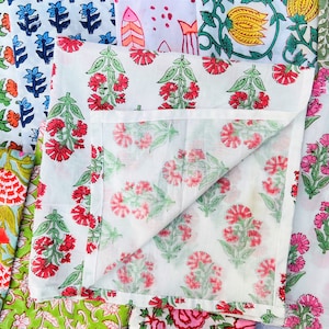 May include: A collection of fabric squares with floral patterns in various colors, including pink, red, blue, green, and yellow. The fabric squares are folded and arranged in a pile.