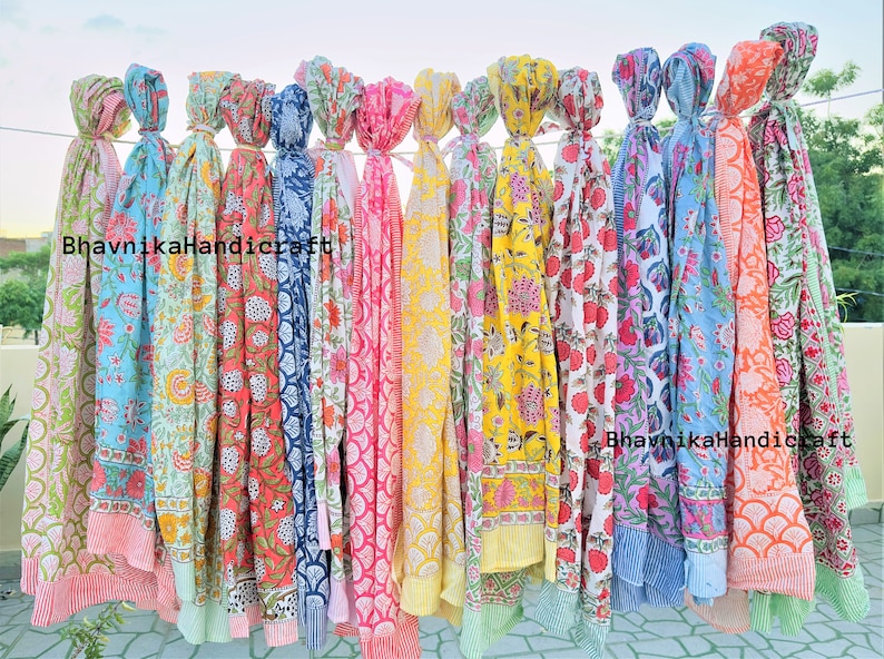 May include: A collection of 12 colorful cotton scarves with floral and geometric patterns. The scarves are arranged in a row and tied together with a string. The text "Bhavnika Handicraft" is visible on the scarves.