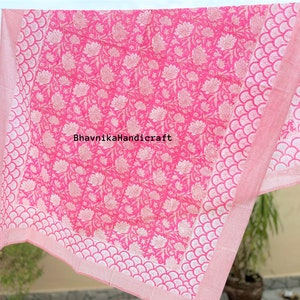 May include: Pink cotton bed sheet with a white floral pattern and a white scalloped border. The sheet is folded and hanging on a clothesline. The text "BhavnikaHandicraft" is printed in the center of the sheet.