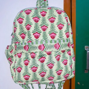 Puede incluir: Una mochila de color verde y rosa con estampado floral y correas ajustables. La mochila tiene un dise&ntilde;o acolchado y un peque&ntilde;o bolsillo en la parte delantera.