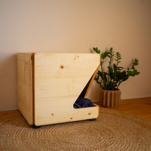 Pu&ograve; includere: Un letto per cani in legno con un bordo rialzato e un'apertura per un letto per animali domestici. Il letto &egrave; realizzato in legno naturale e ha un design semplice e moderno.