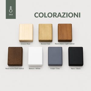 Peut inclure: Sept blocs rectangulaires en bois dispos&eacute;s sur deux rang&eacute;es, pr&eacute;sentant diverses finitions &eacute;tiquet&eacute;es Raw, Oak, Light walnut, Dark walnut, White, Grey et Black. Le logo OKU et le texte COLORAZIONI figurent dans le coin sup&eacute;rieur gauche.