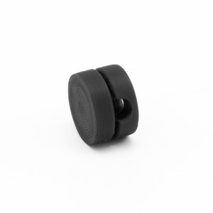 May include: A black plastic cable organizer with a circular shape and a hole in the center.