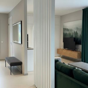 Peut inclure: Un s&eacute;parateur de pi&egrave;ce &agrave; lattes verticales blanches se dresse au centre d'une pi&egrave;ce, compos&eacute; d'une s&eacute;rie de panneaux rectangulaires parall&egrave;les et r&eacute;guli&egrave;rement espac&eacute;s qui s'&eacute;tendent du sol au plafond, cr&eacute;ant une cloison semi-transparente.
