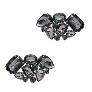 May include: Two pairs of earrings featuring a cluster of black and grey rhinestones in a heart shape.