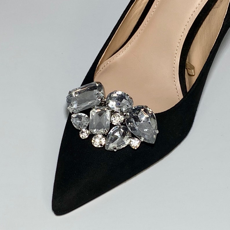 May include: Black suede pointed toe pump with a cluster of clear rhinestone embellishments on the vamp.