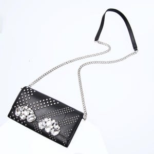 May include: A black leather clutch bag with a silver chain strap and a large rhinestone embellishment.