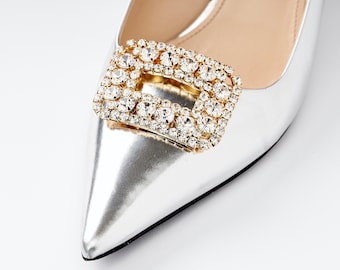 May include: Silver pointed toe women's shoe with a large gold and crystal buckle.