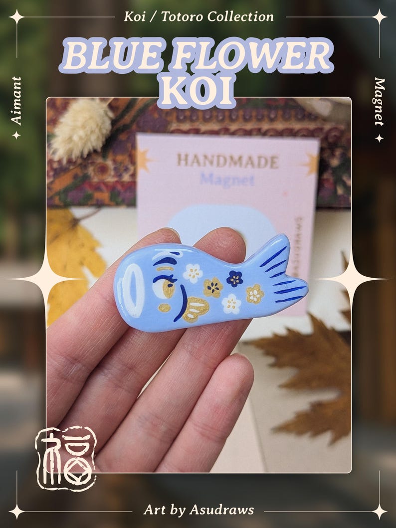 May include: A light blue koi fish magnet with a floral design. The magnet has a white eye and is decorated with gold and white flowers. Text on the image reads "BLUE FLOWER KOI" and "HANDMADE Magnet". The art is by Asudraws.