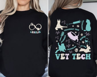 May include: Black sweatshirt with a front design featuring a paw print infinity symbol and the name "LESSLIE". The back design includes various animal silhouettes, medical tools, and the words "VET TECH", "Pharmacy Tech", "Nurse", and "Lab Tech".