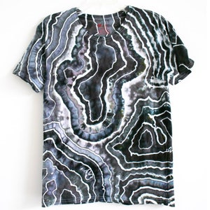 Puede incluir: Camiseta de tie-dye en blanco y negro con un patr&oacute;n abstracto en espiral. El patr&oacute;n se asemeja a un mapa topogr&aacute;fico o una formaci&oacute;n geol&oacute;gica.