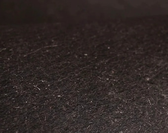 May include: Close-up of a dark brown, textured surface with a subtle sheen. The surface has a fine, grainy texture, similar to the look of leather or suede.