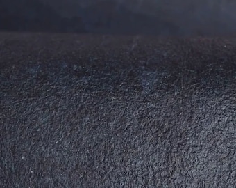 May include: Close-up of a dark blue textured fabric. The fabric has a slightly rough, grainy texture.