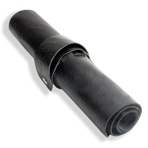 May include: A black leather roll-up mat with a strap closure. The mat is rolled up and tied with the strap.