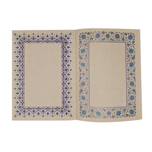 May include: An open book with two pages featuring intricate, decorative borders. The left page has a geometric blue, purple, and white pattern, while the right page displays a floral blue and tan design. Both pages have large, blank, light tan centres.