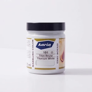 Könnte beinhalten: Ein 125 ml Glas mit Marmorierfarbe der Marke Karin mit schwarzem Deckel. Das Etikett zeigt den Text 101 Titan Beyaz Titanium White, Ebru Boyasi und Marbling Color sowie eine Grafik mit einem weißen Farbmuster und einem Tropfen.