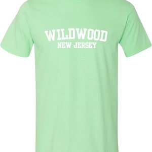 K&ouml;nnte beinhalten: Ein hellgr&uuml;nes T-Shirt mit dem Text "WILDWOOD NEW JERSEY" in Wei&szlig;.