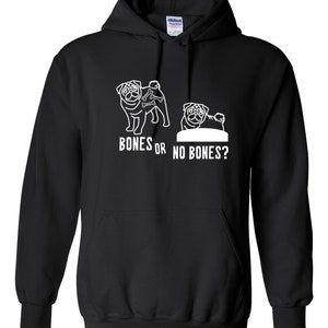 Op de afbeelding: Zwart hoodie met een witte afbeelding van twee mopshonden. Eén mopshond houdt botten vast, de andere niet. De tekst "Bones or No Bones?" staat onder de mopshonden.