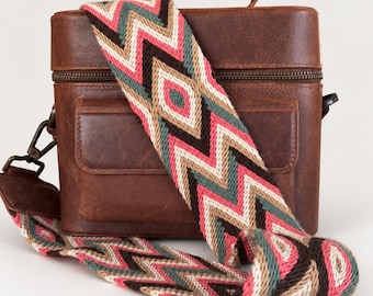 May include: A structured brown leather box bag featuring a top handle and a detachable wide woven shoulder strap. The strap displays a repeating geometric chevron pattern in shades of pink, teal, cream, and dark brown with metal hardware.