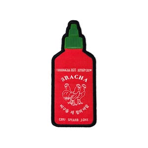 Może przedstawiać: Czerwona i zielona naszywka w kształcie butelki sosu sriracha. Naszywka zawiera napis "3RACHA" i grafikę trzech białych kogutów. U góry znajduje się napis "SRIRACHA HOT HIPHOP CREW".