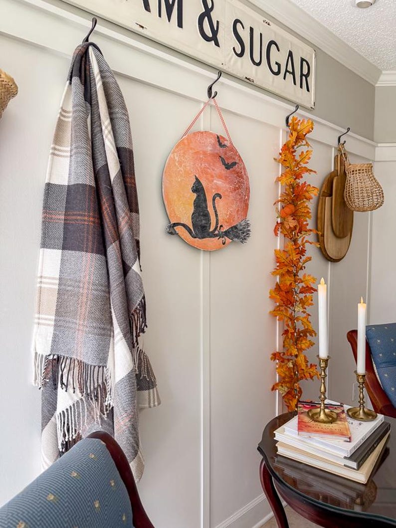 DIY black cat Halloween sign on a fall gallery wall with a plaid throw, autumn leaf garland and brass candlesticks