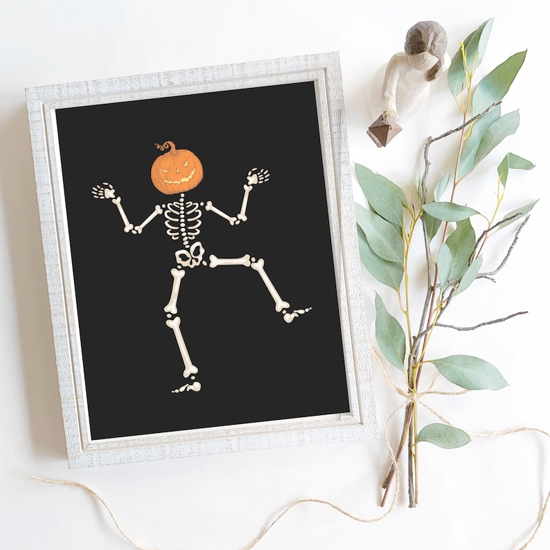 Framed black wall art: a dancing skeleton with an orange pumpkin head, jack-o-lantern Halloween decor.