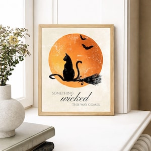 Framed black cat Halloween print beside a window with a vase of greenery, cozy fall home decor